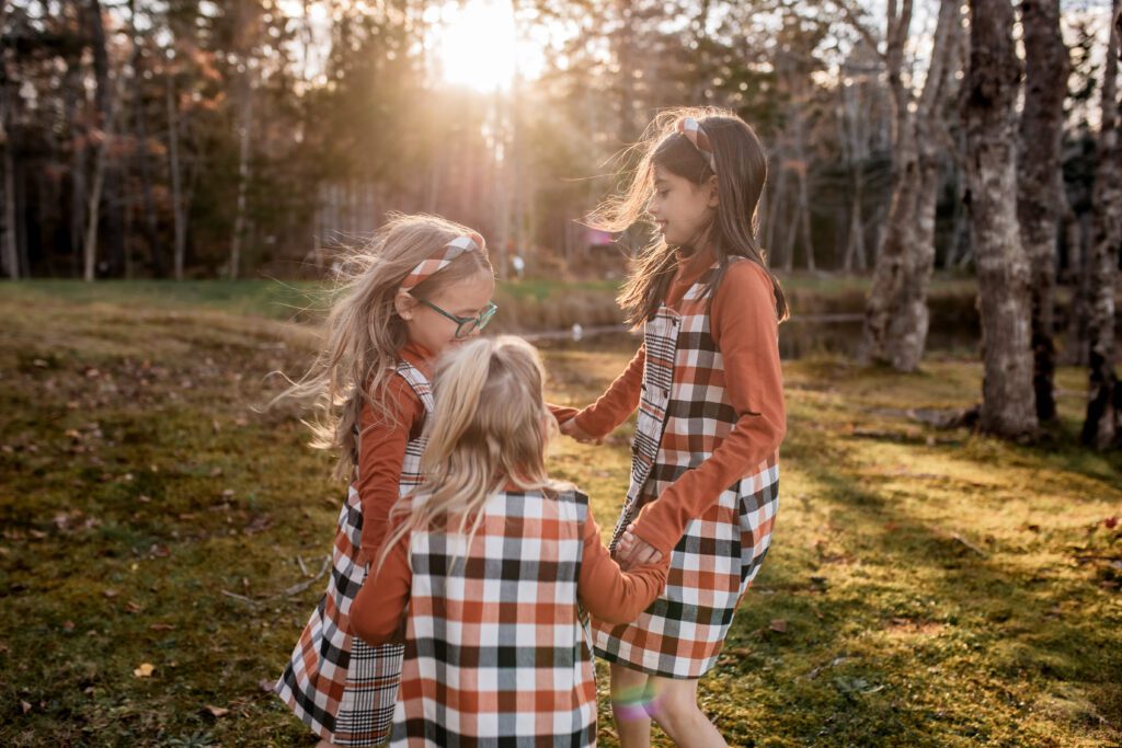 Three sisters playing ring-around-the-rosie during family photo session